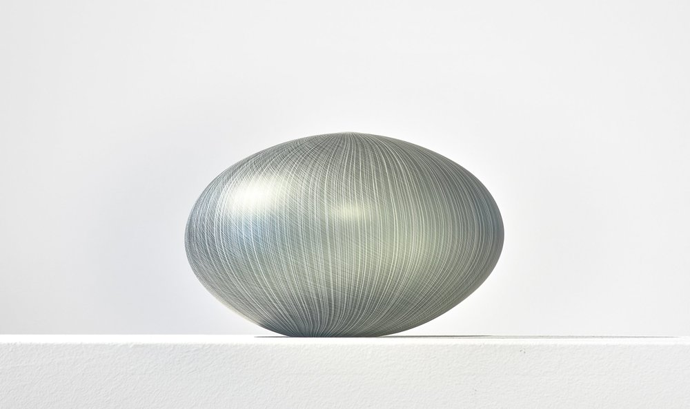 Pale blue gray glass sculpture with a simple round form 