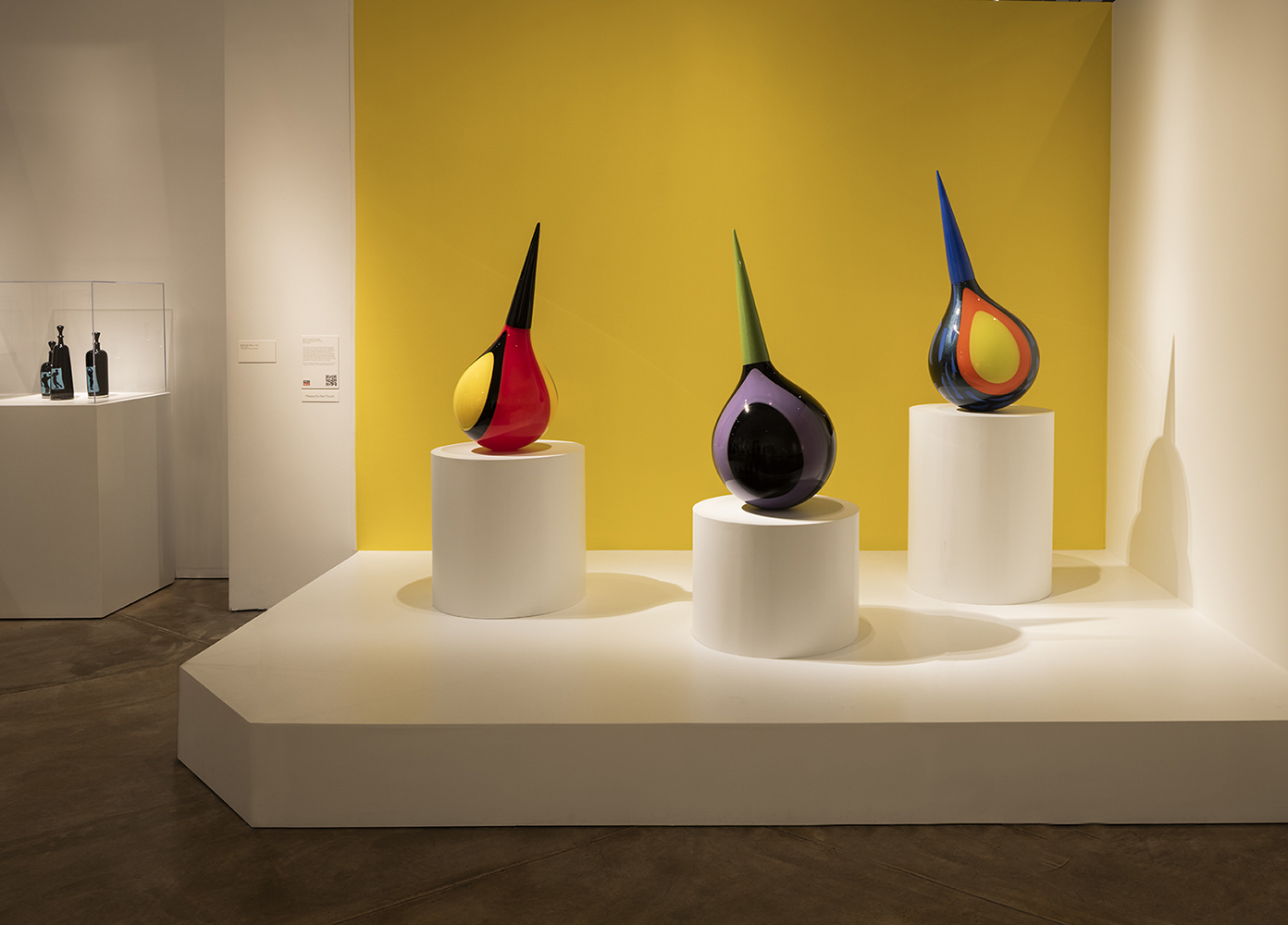 three glass "Stinger" sculptures in front of yellow wall