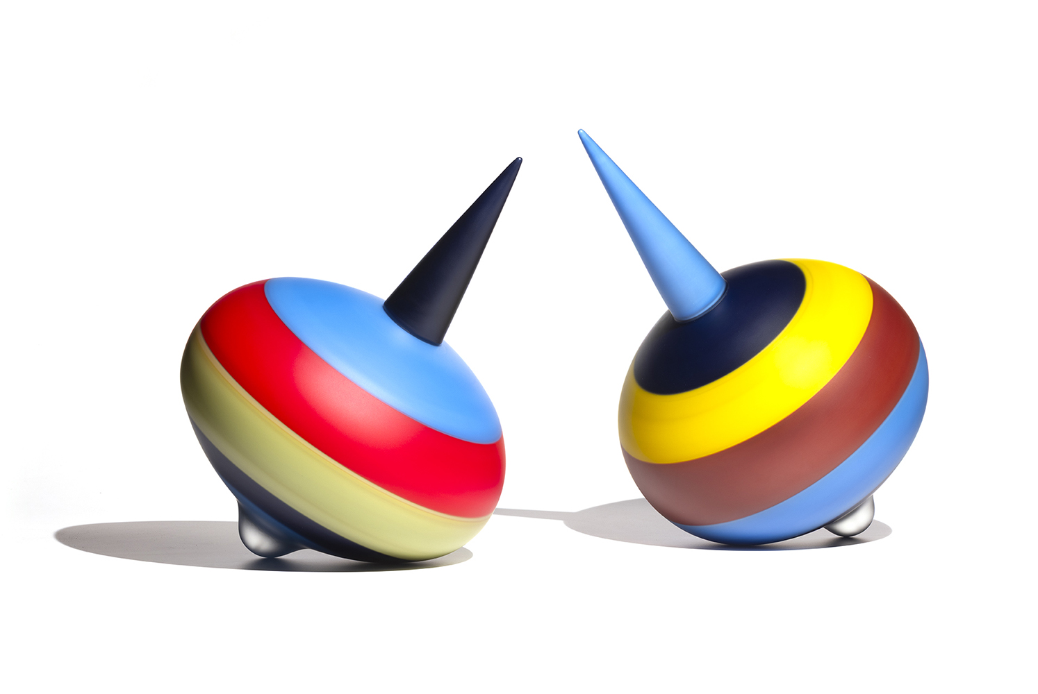 two glass sculptures with round bottoms and pointed tops, bright colored stripes