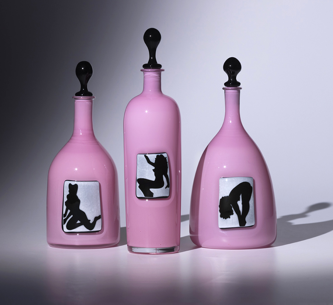 set of three pink glass bottles with images of pin-up girls in black