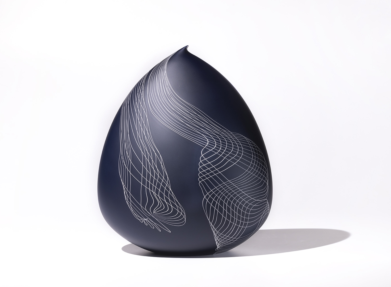 Deep blue glass sculpture with delicate twisting white lines