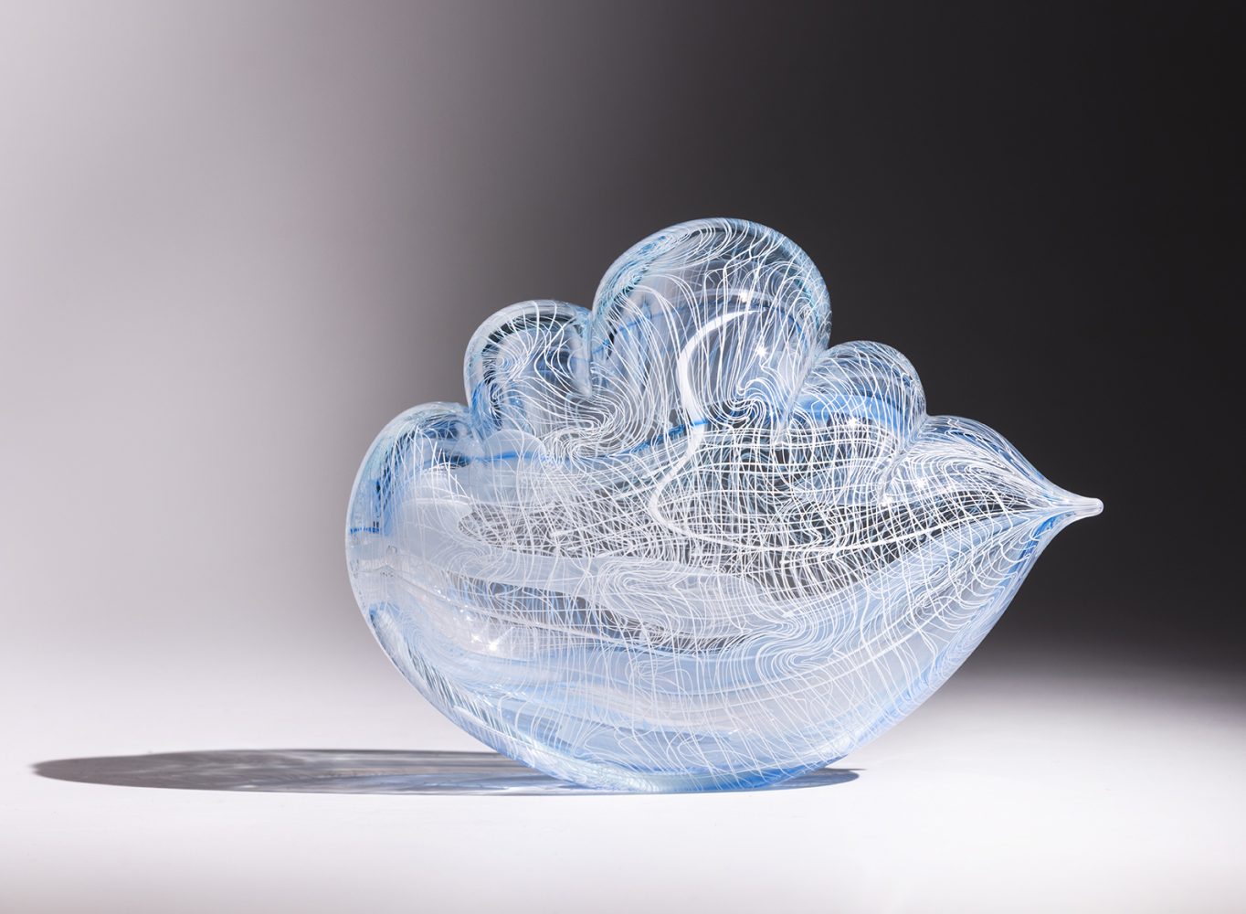 Transparent glass sculpture in cloud shape with white lines and touch of blue