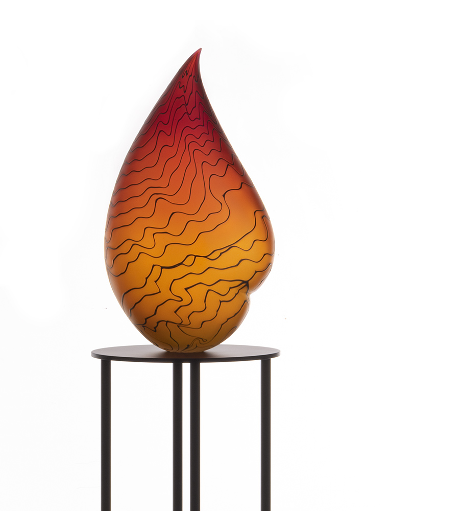 Orange glass sculpture with irregular black lines on a steel oval pedestal 