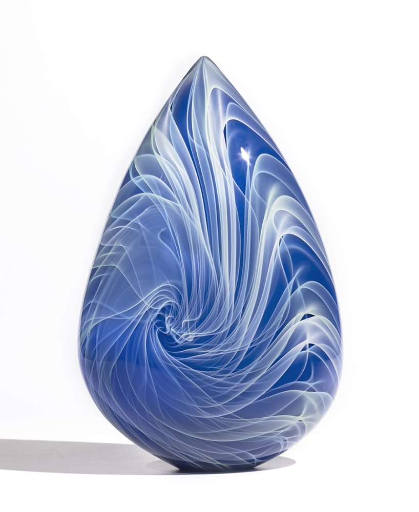 blue glass sculpture in arrowhead shape with flowing white and light green lines
